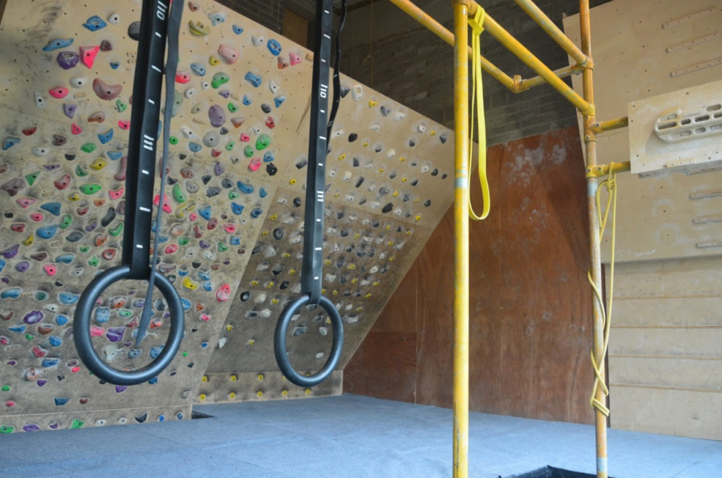 A wide angle photo of the training room at Dublin Climbing Centre, including facilities such as a Moon board, 30° Stōkt board, finger boards, and gymnastic rings