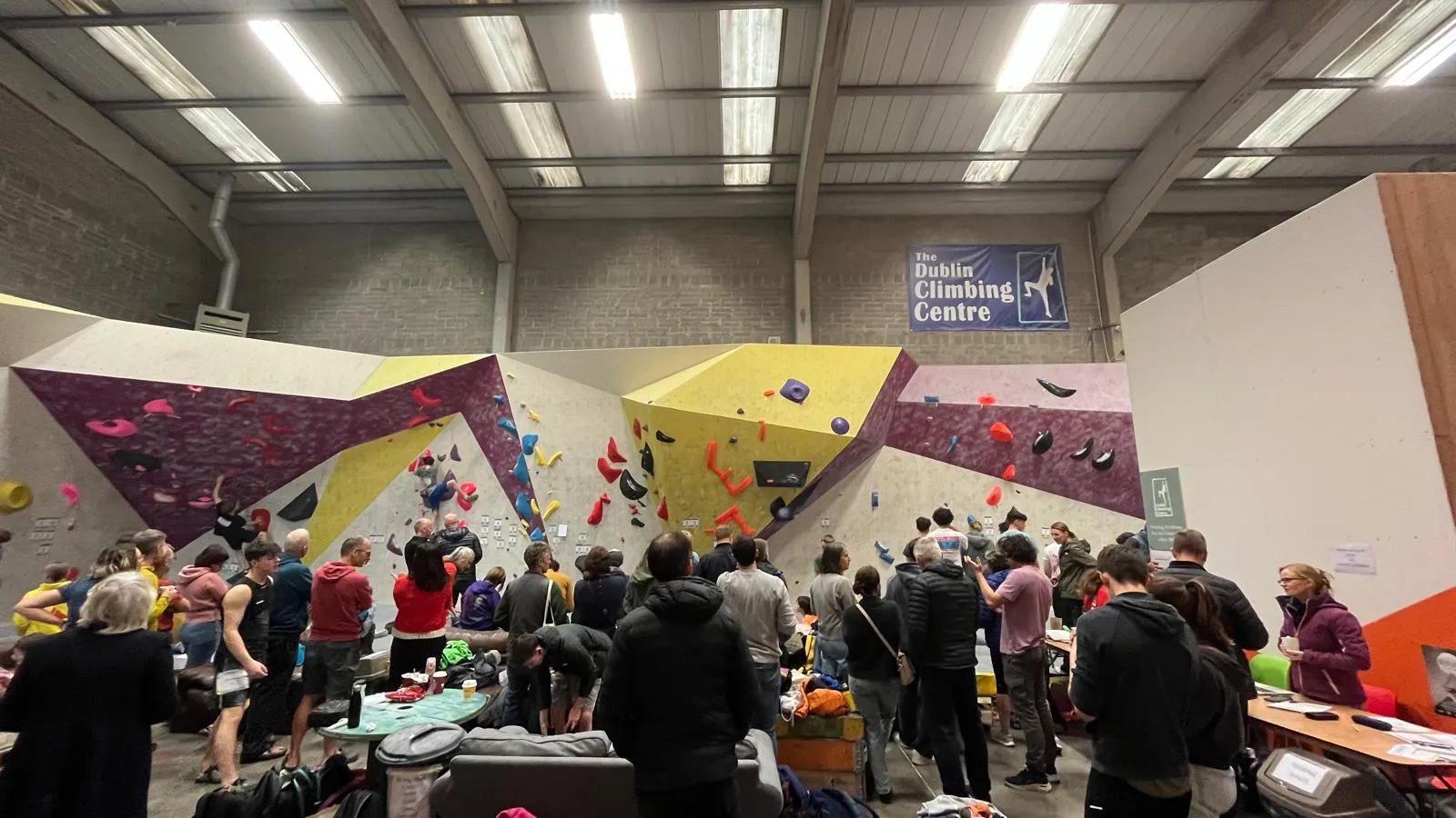 A view of a busy bouldering competition event at Dublin Climbing Centre, with spectators viewing climbers on the boulder wall