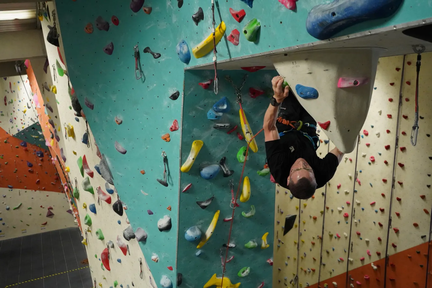 A climber lead climbing upside down across the underside of the overhanging arch at Dublin Climbing Centre
