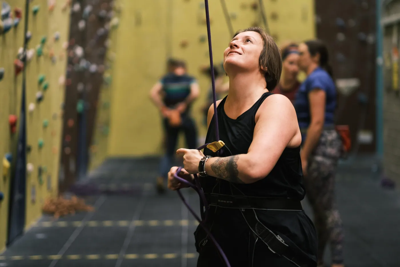 A woman belaying her climbing partner and looking up towards the wall at Dublin Climbing Centre
