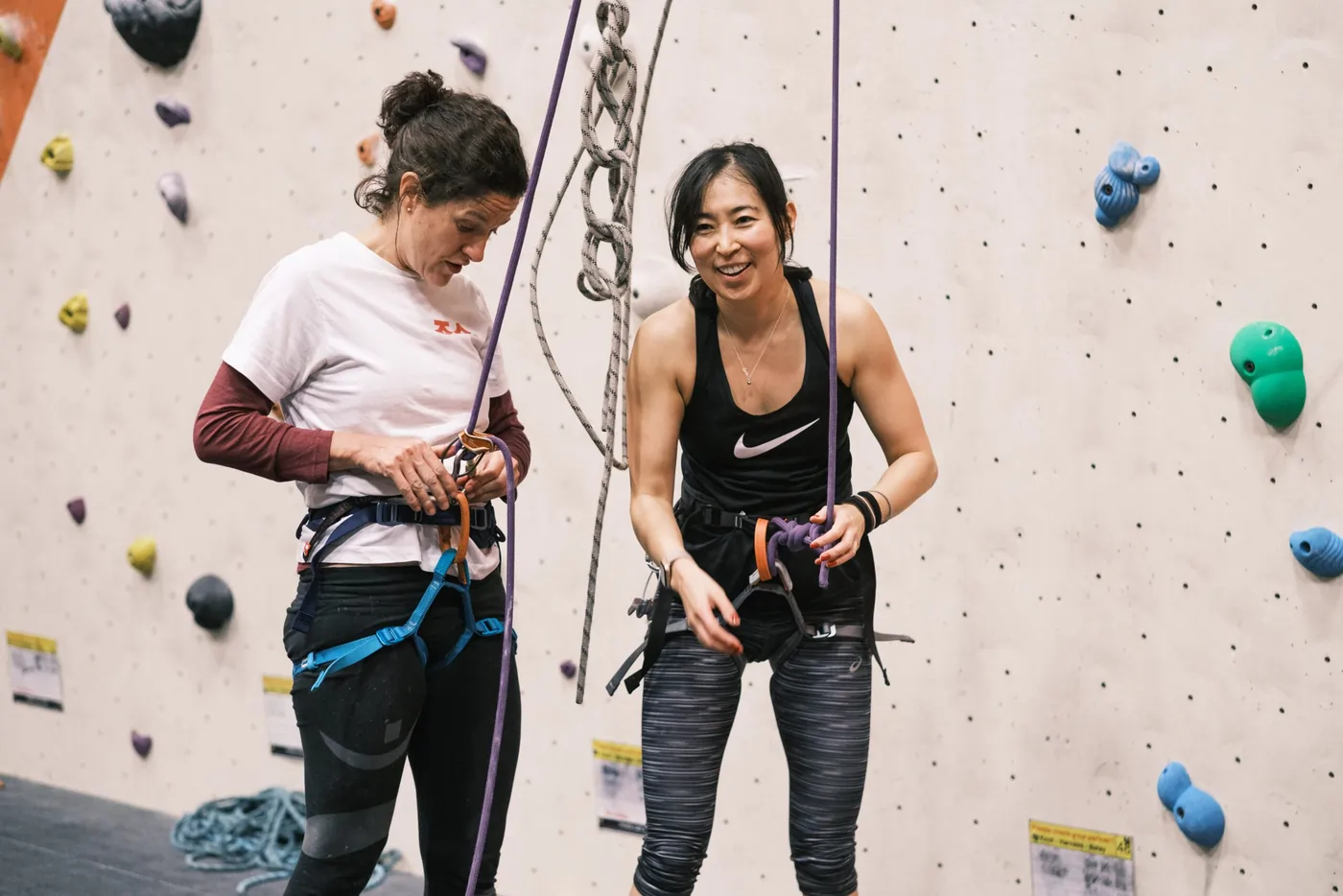 Two female climbers prepare their harnesses to begin climbing at Dublin Climbing Centre