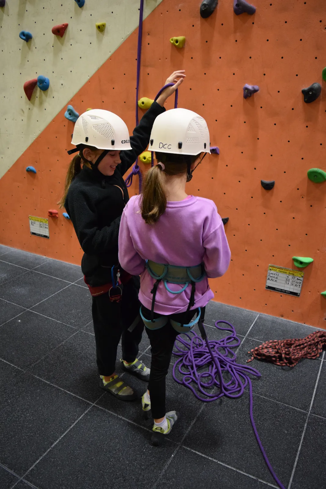 Two young female climbers prepare their harnesses to go climbing at Dublin Climbing Centre
