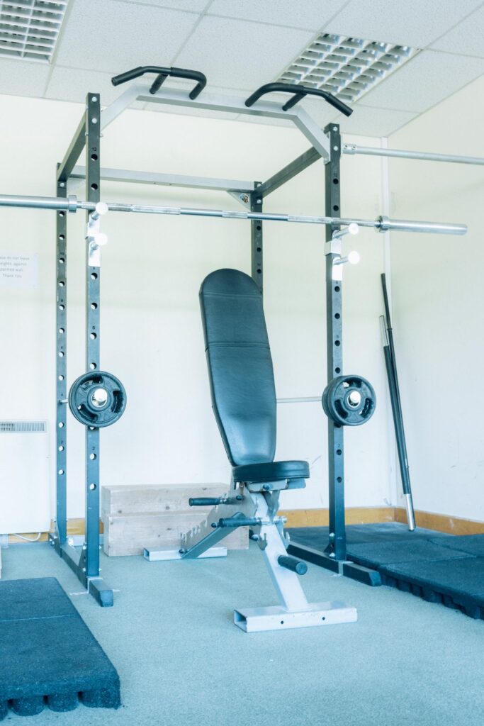 A wide angle photo of the weights room in Dublin Climbing Centre including the squat rack, leg extenstion/curl machine, and various weight bars