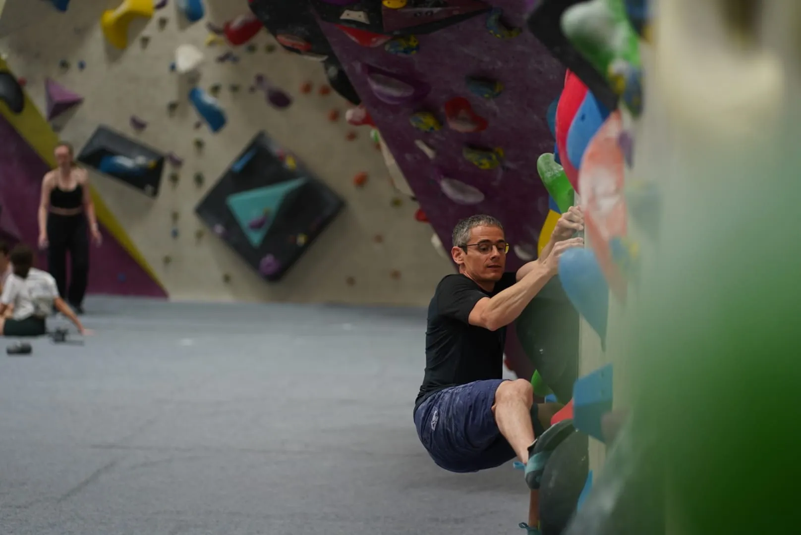 A male boulder climber at the bottom of the bouldering wall looking at his foot movement at Dublin Climbing Centre