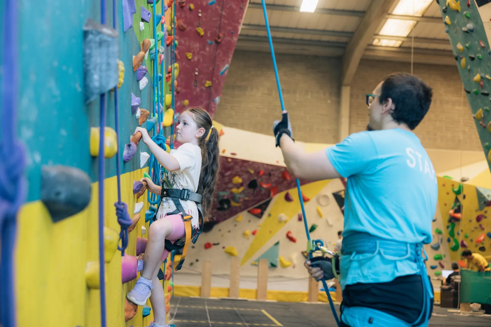 An instructor belaying and guiding a child climber at Dublin Climbing Centre