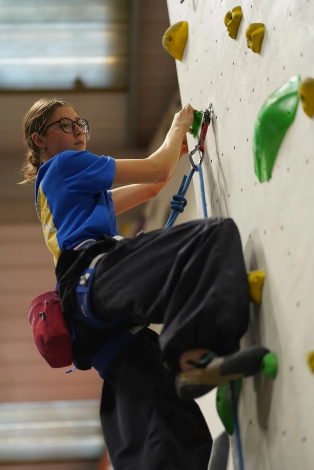 A female climber lead climbing a green coloured route at Dublin Climbing Centre