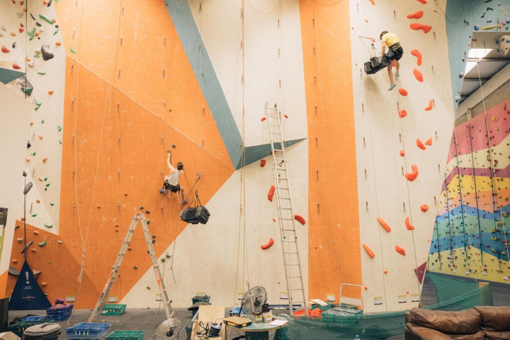 Route setters on ropes setting holds on a tall lead wall at Dublin Climbing Centre