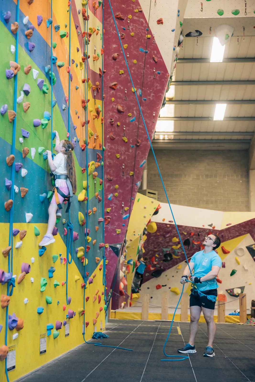 An instructor belays a girl during a school group indoor climbing session at Dublin Climbing Centre